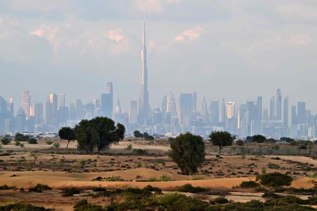 Clouds loom over the Dubai skyline including the Burj Khalifa, the world’s tallest building, in the United Arab Emirates on December 19, 2025. Dubai police urged residents on December 18, 2025, to stay indoors unless it was "absolutely necessary" as heavy rainfall was expected in the desert country which saw record downpours last year. (Photo by Giuseppe CACACE / AFP)