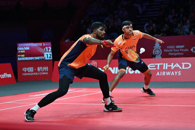 India’s Satwiksairaj Rankireddy and Chirag Shetty play a point during their men’s doubles match against Malaysia’s Aaron Chia and Soh Wooi Yik at the BWF Badminton World Tour Finals at the Hangzhou Olympic Sports Centre Gymnasium in Hangzhou, in eastern China's Zhejiang province on December 19, 2025. (Photo by Jade Gao / AFP)