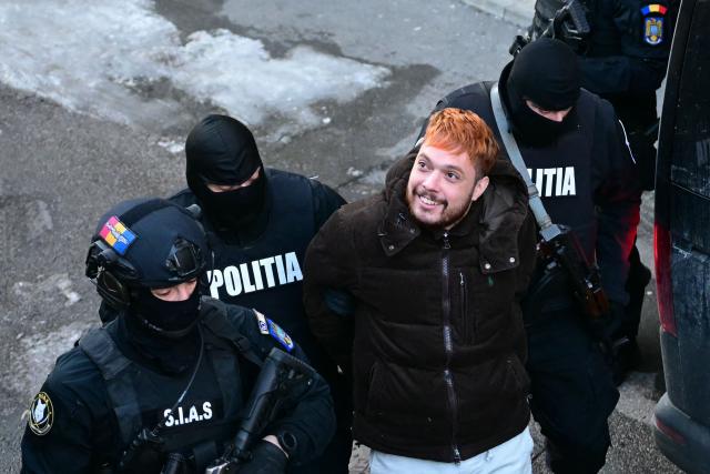 (FILES) French convict and drug trafficker Mohamed Amra (C) is escorted by policemen out of the Court of Appeal in Bucharest on February 23, 2025, one day after his arrest under an European arrest warrant. (Photo by Daniel MIHAILESCU / AFP)