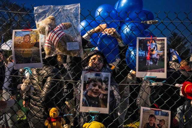 A woman ties balloons to a fence at the end of a silent march in tribute to two children who died in the explosion of a residential building, in Trevoux, central-eastern France, on December 19, 2025. The explosion that killed two children aged 3 and 5 on December 15 in a residential building in Trevoux, was caused by a woman who committed suicide by turning on the gas in a neighbouring flat. (Photo by ARNAUD FINISTRE / AFP)