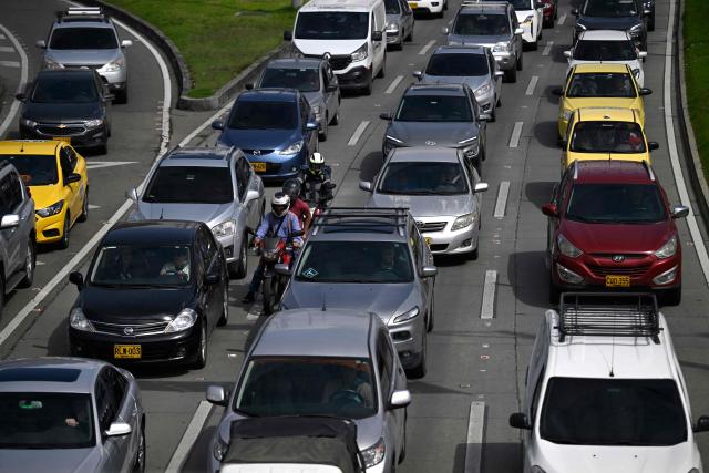 Motorcyclists ride amid cars during a traffic jam in Bogota on December 19, 2025. (Photo by Pablo VERA / AFP)