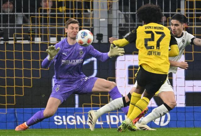 Moenchengladbach's German goalkeeper #33 Moritz Nicolas and Dortmund's German forward #27 Karim Adeyemi vie for the ball during the German first division Bundesliga football match between Borussia Dortmund and Borussia Moenchengladbach in Dortmund on December 19, 2025. (Photo by UWE KRAFT / AFP) / DFL REGULATIONS PROHIBIT ANY USE OF PHOTOGRAPHS AS IMAGE SEQUENCES AND/OR QUASI-VIDEO
