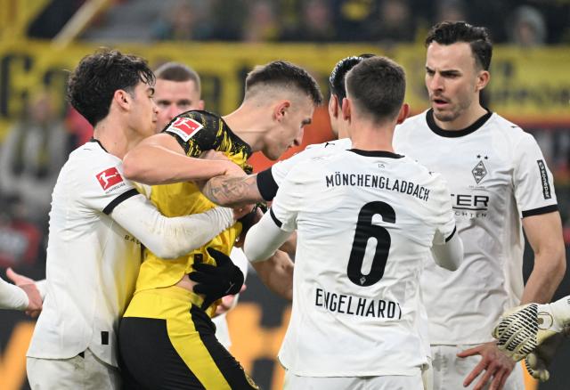 Moenchengladbach's US midfielder #13 Giovanni Reyna holds Dortmund's German defender #04 Nico Schlotterbeck during the German first division Bundesliga football match between Borussia Dortmund and Borussia Moenchengladbach in Dortmund on December 19, 2025. (Photo by UWE KRAFT / AFP) / DFL REGULATIONS PROHIBIT ANY USE OF PHOTOGRAPHS AS IMAGE SEQUENCES AND/OR QUASI-VIDEO