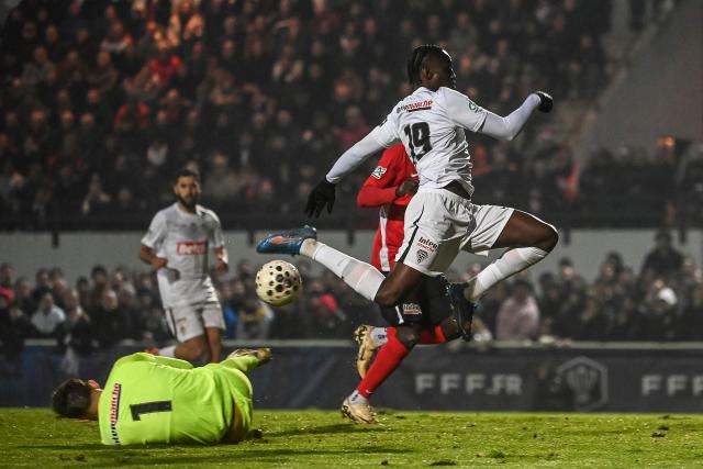 Angers' French forward #19 Sidiki Cherif (R) fights for the ball with Les Herbiers'goalkeeper #01 Bastien Rempp (L) during the French Cup round of 64 football match between Vendee Les Herbiers football and Angers SCO at the 'Massabielle' stadium in Les Herbiers, western France, on December 19, 2025. (Photo by JEAN-FRANCOIS MONIER / AFP)