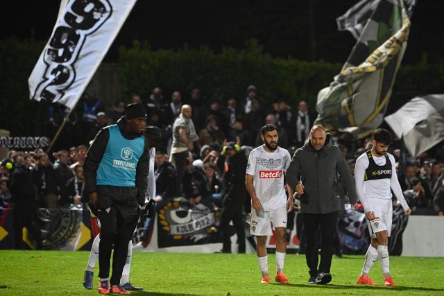 Angers' French head coach Alexandre Dujeux (2nd R) walks off the pitch after winning the French Cup round of 64 football match between Vendee Les Herbiers football and Angers SCO at the 'Massabielle' stadium in Les Herbiers, western France, on December 19, 2025. (Photo by JEAN-FRANCOIS MONIER / AFP)