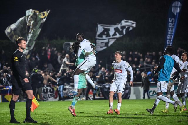 Angers' players celebrate after winning the French Cup round of 64 football match between Vendee Les Herbiers football and Angers SCO at the 'Massabielle' stadium in Les Herbiers, western France, on December 19, 2025. (Photo by JEAN-FRANCOIS MONIER / AFP)