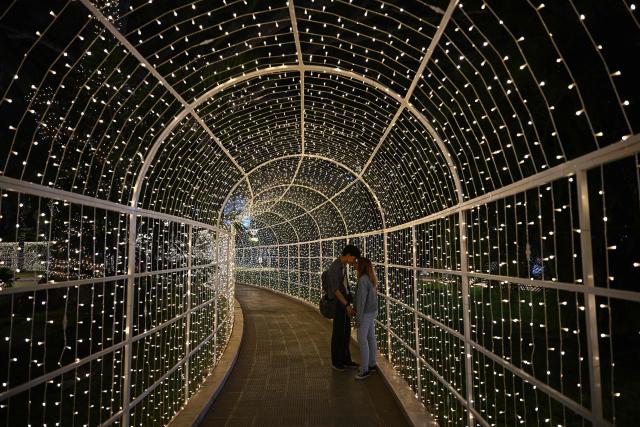 A couple stands inside a Christmas decoration at Los Proceres boulevard in Caracas on December 19, 2025. (Photo by Federico PARRA / AFP)