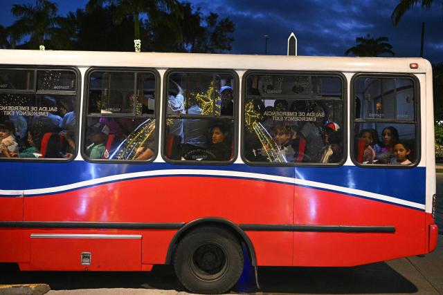 Passengers travel on a bus as Christmas decorations are reflected on its windows at Los Proceres boulevard in Caracas on December 19, 2025. (Photo by Federico PARRA / AFP)