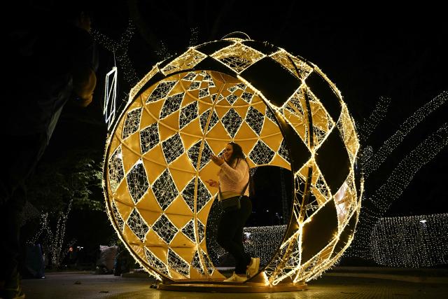 A woman walks inside a Christmas decoration at Los Proceres boulevard in Caracas on December 19, 2025. (Photo by Federico PARRA / AFP)