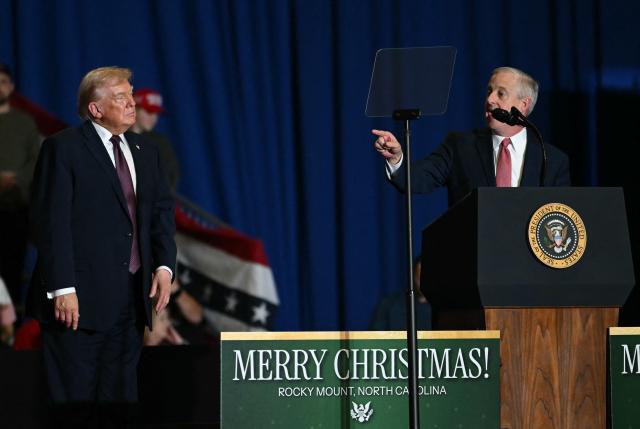 US President Donald Trump looks on as former chairperson of the Republican National Committee Michael Whatley (R) speaks during a political rally in Rocky Mount, North Carolina on December 19, 2025. (Photo by ANDREW CABALLERO-REYNOLDS / AFP)