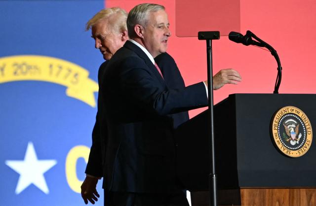 US President Donald Trump walks behind former chairperson of the Republican National Committee Michael Whatley as he prepares to speak during a political rally in Rocky Mount, North Carolina on December 19, 2025. (Photo by ANDREW CABALLERO-REYNOLDS / AFP)