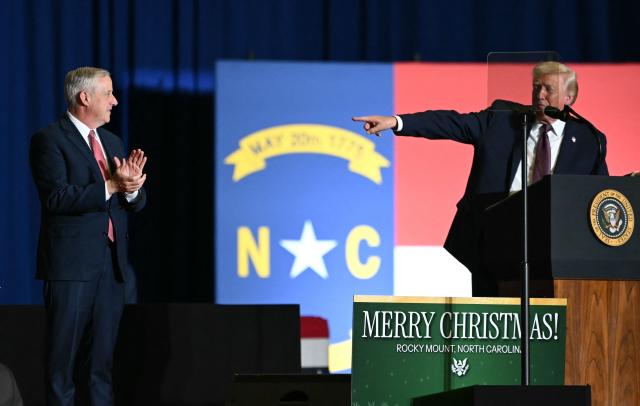 US President Donald Trump points to former chairperson of the Republican National Committee Michael Whatley (L) during a political rally in Rocky Mount, North Carolina on December 19, 2025. (Photo by ANDREW CABALLERO-REYNOLDS / AFP)