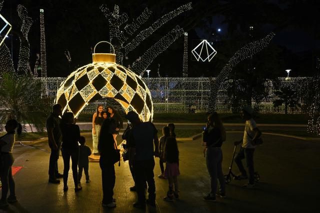 People enjoy Christmas decorations at Los Proceres boulevard in Caracas on December 19, 2025. (Photo by Federico PARRA / AFP)
