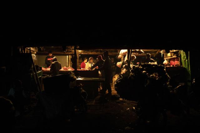 This photo taken on December 20, 2025 shows people walking through a market area in Lashio in Myanmar's northern Shan state. (Photo by AFP)