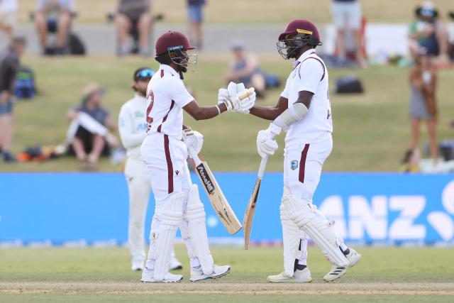 West Indies' Kavem Hodge (L) celebrates his century with Anderson Phillip (R) during day three of the 3rd international Test cricket match between New Zealand and West Indies at Bay Oval in Mount Maunganui on December 20, 2025. (Photo by Michael Bradley / AFP)