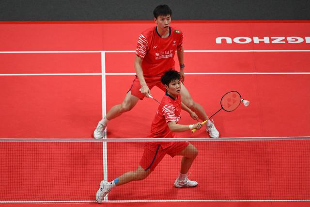 China’s Feng Yan Zhe and Huang Dongping (bottom) play a point during their mixed doubles semifinal match against Japan’s Hiroki Midorikawa and Natsu Saito at the BWF Badminton World Tour Finals at the Hangzhou Olympic Sports Centre Gymnasium in Hangzhou, in eastern China's Zhejiang province on December 20, 2025. (Photo by Jade Gao / AFP)