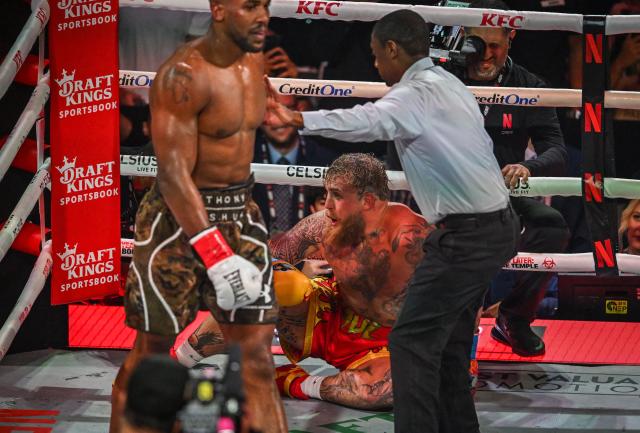 Referee Christopher Young counts over US boxer and influencer Jake Paul as he sits on the floor during his fight against British boxer Anthony Joshua (L) in a non-title heavyweight bout at the Kaseya Center in Miami, Florida, on December 19, 2025. (Photo by Giorgio VIERA / AFP)