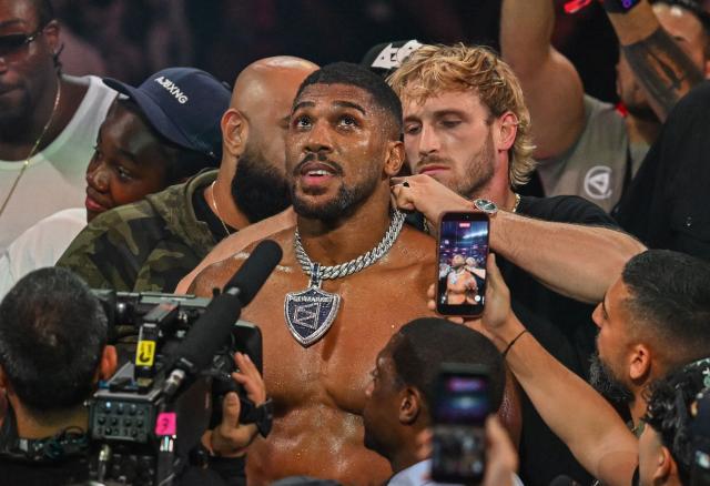 YouTuber Logan Paul puts a medal around the neck of British boxer Anthony Joshua as he celebrates after defeating US boxer and influencer Jake Paul (off frame) in a non-title heavyweight bout at the Kaseya Center in Miami, Florida, on December 19, 2025. (Photo by Giorgio VIERA / AFP)