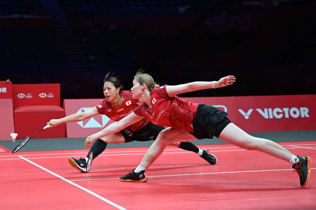 Japan’s Yuki Fukushima (L) and Mayu Matsumoto play a point during their women’s doubles semifinal match against Malaysia’s Pearly Tan and Thinaah Muralitharan at the BWF Badminton World Tour Finals at the Hangzhou Olympic Sports Centre Gymnasium in Hangzhou, in eastern China's Zhejiang province on December 20, 2025. (Photo by Jade Gao / AFP)