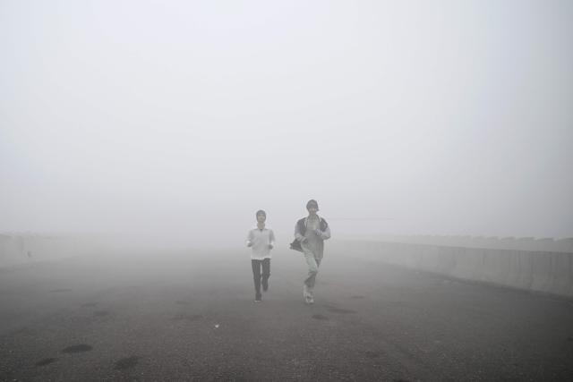 Youths jog amid dense smog during a winter morning in New Delhi on December 20, 2025. (Photo by Arun SANKAR / AFP)