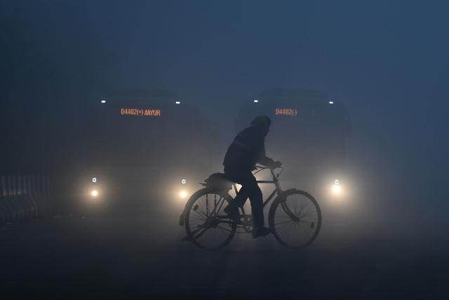 A cyclist moves along a road amid dense smog during a winter morning in New Delhi on December 20, 2025. (Photo by Arun SANKAR / AFP)