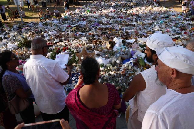 Members of the Hindu community lay a wreath as mourners gather in front of tributes laid in memory of victims of a shooting at Bondi Beach, in Sydney on December 20, 2025. Father-and-son gunmen are accused of firing into crowds at a beachside Jewish festival on December 14, killing 15 in an attack authorities linked to "Islamic State ideology". (Photo by DAVID GRAY / AFP)