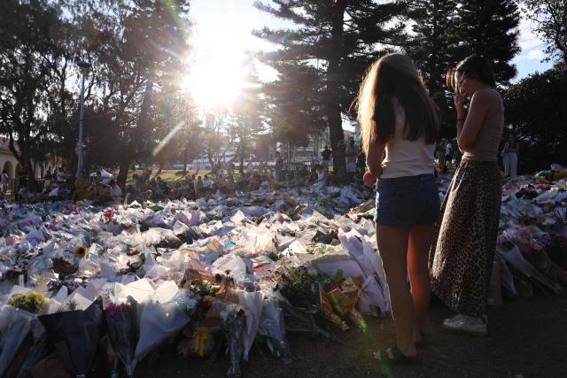 Mourners gather in front of tributes in memory of the victims of a shooting at Bondi Beach, in Sydney on December 20, 2025. Father-and-son gunmen are accused of firing into crowds at a beachside Jewish festival on December 14, killing 15 in an attack authorities linked to "Islamic State ideology". (Photo by DAVID GRAY / AFP)