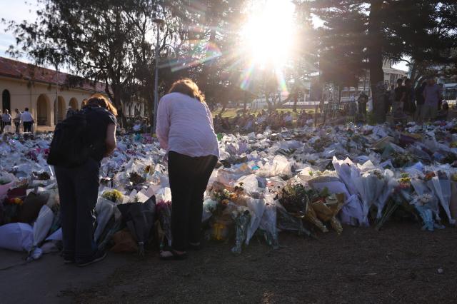 Mourners gather in front of tributes in memory of the victims of a shooting at Bondi Beach, in Sydney on December 20, 2025. Father-and-son gunmen are accused of firing into crowds at a beachside Jewish festival on December 14, killing 15 in an attack authorities linked to "Islamic State ideology". (Photo by DAVID GRAY / AFP)