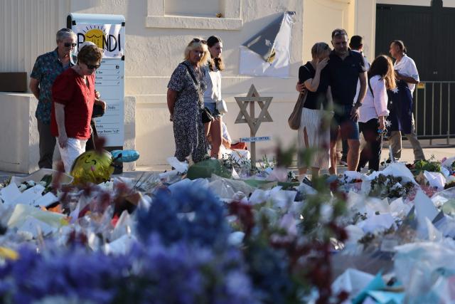 Mourners gather in front of tributes laid in memory of victims of a shooting at Bondi Beach, in Sydney on December 20, 2025. Father-and-son gunmen are accused of firing into crowds at a beachside Jewish festival on December 14, killing 15 in an attack authorities linked to "Islamic State ideology". (Photo by DAVID GRAY / AFP)