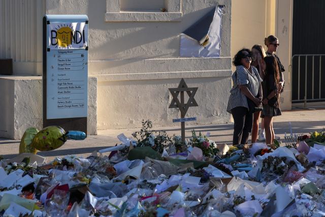 Mourners gather in front of tributes laid in memory of victims of a shooting at Bondi Beach, in Sydney on December 20, 2025. Father-and-son gunmen are accused of firing into crowds at a beachside Jewish festival on December 14, killing 15 in an attack authorities linked to "Islamic State ideology". (Photo by DAVID GRAY / AFP)