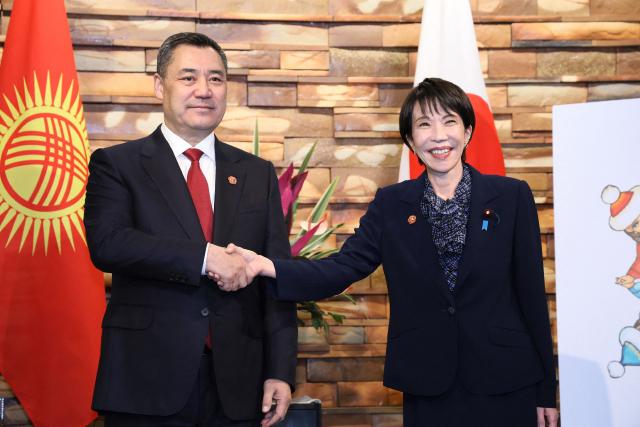 Japan's Prime Minister Sanae Takaichi (R) shakes hands with Kyrgyzstan's President Sadyr Japarov ahead of their summit meeting, at the Prime Minister's Office in Tokyo on December 20, 2025. (Photo by JIJI Press / AFP) / Japan OUT