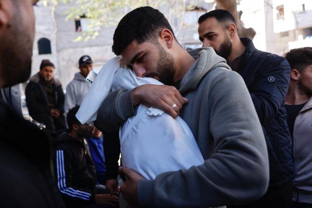 A Palestinian man carries the body of his 5-month-old brother, Ahmed Al-Nader, who was reportedly killed the previous day along with other family members in an Israeli shelling on a school-turned-shelter in the Tuffah neighbourhood of Gaza City, ahead of his funeral on December 20, 2025. Gaza's civil defence agency said Israeli shelling on a school-turned-shelter killed five people on December 19, 2025, while the military said it had fired at "suspicious individuals". The ceasefire that came into effect on October 10 has halted the fighting between Israel and Hamas, but it remains fragile with each side accusing the other of violating its terms. (Photo by Omar AL-QATTAA / AFP)