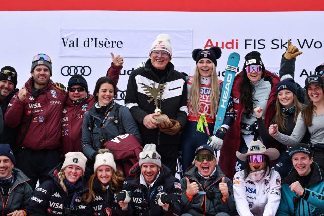 Third-placed US Lindsey Vonn (C-R) celebrates with her father Alan Kildow (C) and members of her team during the podium ceremony after competing in the women's downhill race part of the FIS Alpine Ski World Cup 2025-2026, in Val d'Isere, south western France, on December 20, 2025. (Photo by Jeff PACHOUD / AFP)