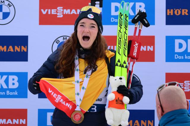 First placed France's Lou Jeanmonnot celebrates with the world cup leader's yellow bib on the podium of the women's 10km pursuit event of the IBU Biathlon World Cup, in Le Grand Bornand, near Annecy, southeastern France, on December 20, 2025. (Photo by Olivier CHASSIGNOLE / AFP)