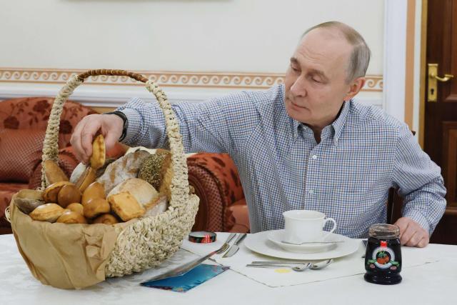 In this pool photograph distributed by Russian state agency Sputnik, Russia's President Vladimir Putin tastes pastries from a bakery sent by its owner following his annual end-of-year press conference, in Moscow, on December 20, 2025.  (Photo by Mikhail METZEL / POOL / AFP)