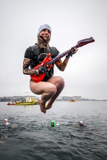 A swimmer dressed as a rocker dives into Lake Geneva during the 87th "Coupe de Noel" (Christmas Cup) swimming race in Geneva on December 20, 2025. More than 4,200 participants took part in the traditional two-day event, a 120m-long swim off Geneva's banks into the 8.9 degrees Celsius water. (Photo by Fabrice COFFRINI / AFP)