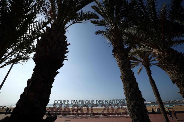 People walk along the corniche promenade in Agadir, Morocco, on 20 December 2025, on the eve of the kick-off of the Africa Cup of Nations (CAN) football tournament. Morocco take on Comoros in the opening game on December 21. (Photo by FRANCK FIFE / AFP)