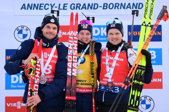 Second placed France's Emilien Jacquelin (L), first placed Norway's Johan-Olav Botn and third placed Norway's Johannes Dale-Skjevdal celebrate on the podium of the men's 12,5km pursuit event of the IBU Biathlon World Cup, in Le Grand Bornand, near Annecy, southeastern France, on December 20, 2025. (Photo by Olivier CHASSIGNOLE / AFP)