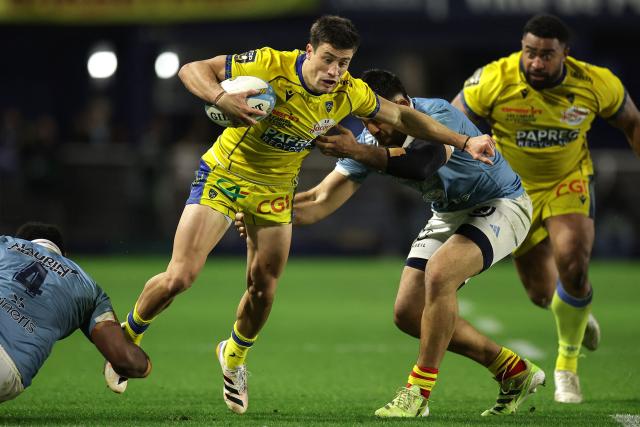 Clermont's Argentine wing Bautista Delguy (C) is tackled during the French Top14 rugby union match between USA Perpignan and ASM Clermont Auvergne at the Aime-Giral stadium in Perpignan, south-western France on Dcember 20, 2025. (Photo by Valentine CHAPUIS / AFP)