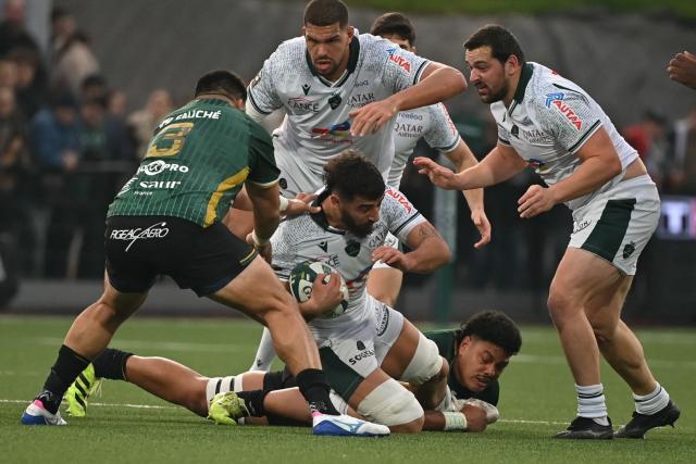 Pau's French back row Sacha Zegueur (bottom, C) is tackled during the French Top14 rugby union match between US Montauban and Paloise Bearn Pyrenees (Pau) at Stade Sapiac in Montauban, south-western France on December 20, 2025. (Photo by Matthieu RONDEL / AFP)