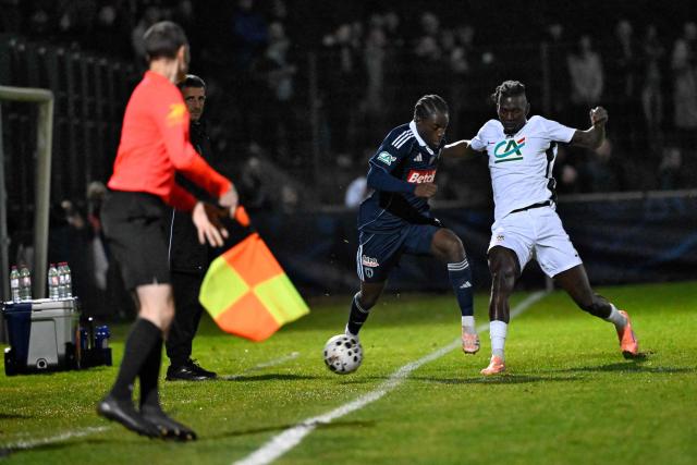 Paris FC’s French forward #07 Jonathan Ikone (L) fights for the ball with Raon-l’Etape's midfielder #09 Assane Toure during the French Cup round of 64 football match between Raon l’Etape and Paris FC at the Paul-Gasser Stadium, in Raon-l'Etape, eastern France, on December 20, 2025. (Photo by Jean-Christophe VERHAEGEN / AFP)