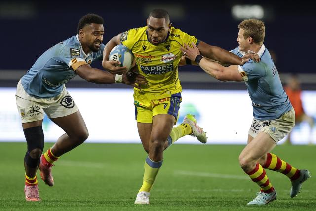 Clermont's Fijian centre Alivereti Loaloa (C) is tackled during the French Top14 rugby union match between USA Perpignan and ASM Clermont Auvergne at the Aime-Giral stadium in Perpignan, south-western France on Dcember 20, 2025. (Photo by Valentine CHAPUIS / AFP)