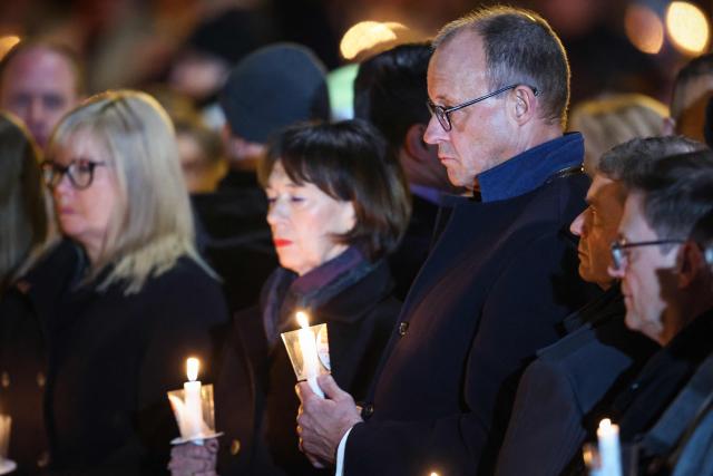 People including German Chancellor Friedrich Merz (3rd R) with his wife Charlotte Merz hold candles outside St John's Church (Johanniskirche) one year after a deadly SUV rampage in which six people were killed and more than 300 wounded at the Christmas market at the Old market square in Magdeburg, eastern Germany, on December 20, 2025. (Photo by Ronny HARTMANN / AFP)