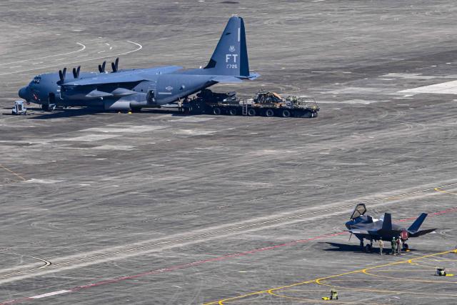 A US Air Force C-130 Hercules (L) and a US Air Force F-35A fighter sit on the tarmac at José Aponte de la Torre Airport, formerly Roosevelt Roads Naval Station, on December 20, 2025 in Ceiba, Puerto Rico. Aircraft movements and coordinated exercises were observed throughout the day as part of heightened regional military readiness linked to ongoing operations at US military bases and maritime security efforts in the Caribbean. President Donald Trump administration is conducting a military campaign in the Caribbean and eastern Pacific, deploying naval and air forces for what it calls an anti-drugs offensive. (Photo by Miguel J. Rodriguez Carrillo / AFP)