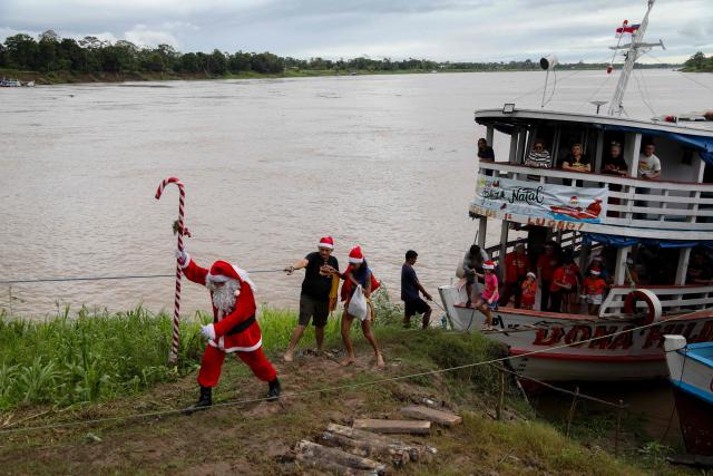 Volunteer Jorge Alberto Barrozo, dressed as Santa Claus, walks to deliver gifts to children in riverside communities in the rural area of Careiro da Varzea, Amazonas state, Brazil on December 20, 2025. Since 1998, the Friends of Santa Claus volunteer group has been promoting Christmas for children in rural and riverside communities in the Amazon rainforest. (Photo by Michael DANTAS / AFP)