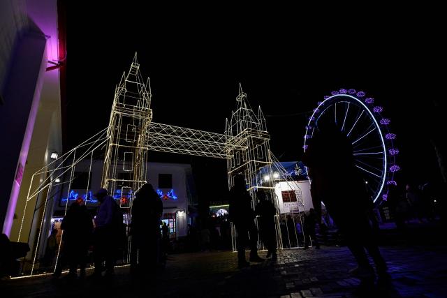 People walk past traditional Christmas lights at the Monserrate Mountain in Bogota on December 20, 2025. (Photo by Pablo VERA / AFP)