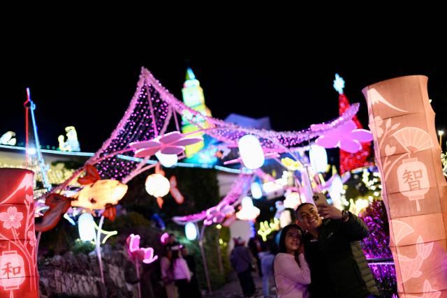 A couple takes a selfie with the traditional Christmas lights at the Monserrate Mountain in Bogota on December 20, 2025. (Photo by Pablo VERA / AFP)