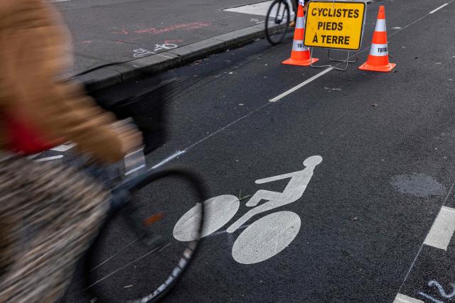 (FILES) A bicycle ridEs on a bicycle path in Paris on November 12, 2025. The construction of the cycling paths in the Ile-de-France region has slowed down due to budget constraints affecting the departments, which partially fund these large-scale projects. Since February 2020, 241 km of cycle paths separated by curbs have been built, according to the public agency Île-de-France Mobilités, primarily under the auspices of the departments. (Photo by JOEL SAGET / AFP)