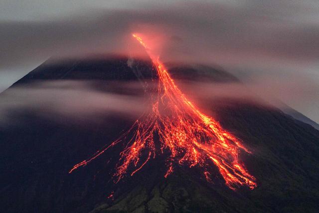 Mount Merapi spews lava onto its slopes as seen from Tunggularum village in Sleman, Yogyakarta, on December 20, 2025. (Photo by DEVI RAHMAN / AFP)