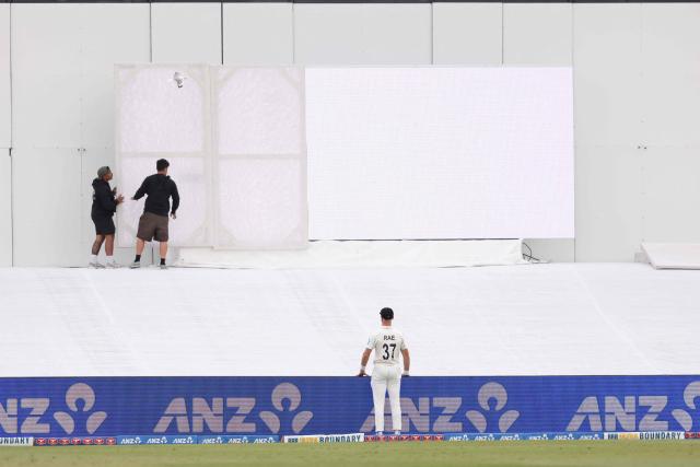 Groundsmen cover the broken digital screen during day four of the 3rd international Test cricket match between New Zealand and West Indies at Bay Oval in Mt Maunganui on December 21, 2025. (Photo by Michael Bradley / AFP)